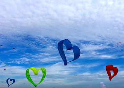 Low angle view of heart balloons against sky