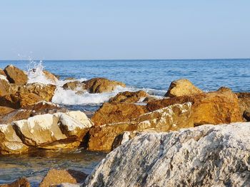 Rocks on beach against clear sky