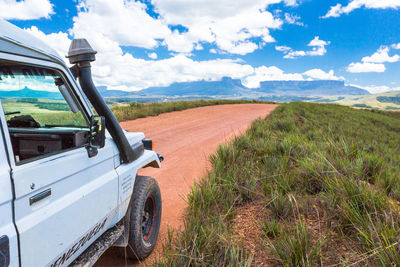 Panoramic view of road amidst field against sky