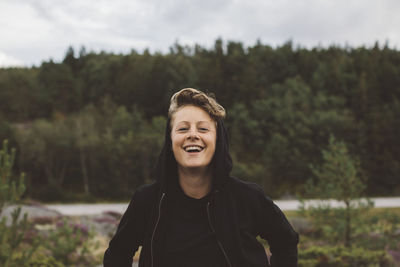 Portrait of smiling young man standing against trees
