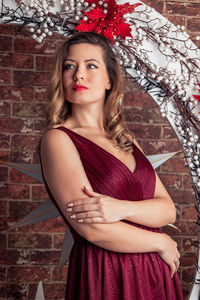 Portrait of young woman standing against wall