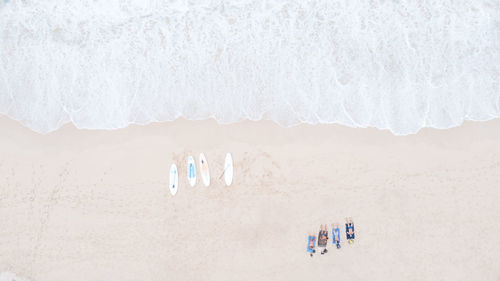 Tourist man lying on the sand and four surfboard are placed on the sandy beach and sea wave