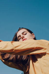 Portrait of young woman against blue sky