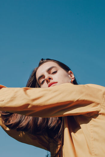 Portrait of young woman against blue sky