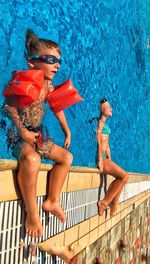 Tilt shot of siblings in swimming pool on sunny day