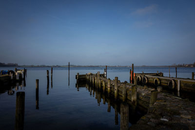 Wooden posts in sea against sky