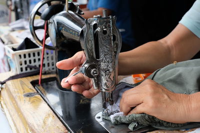 Cropped hands sewing textile on machine