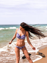 Full length of young woman standing at beach