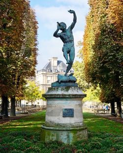 Statue in city against blue sky