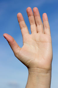 Close-up of human hand against sky