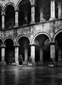 Rear view of woman standing at courtyard against old building