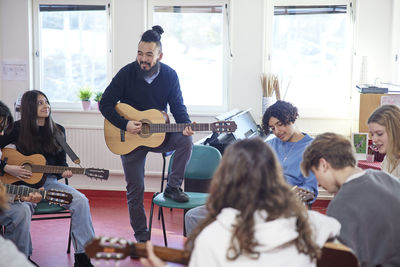 Teenagers attending guitar lesson