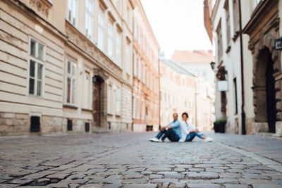 People sitting on street amidst buildings in city