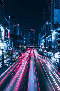 Light trails on city street amidst buildings at night