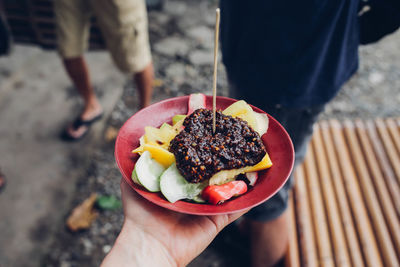 Close-up of hand holding fruit salad on street