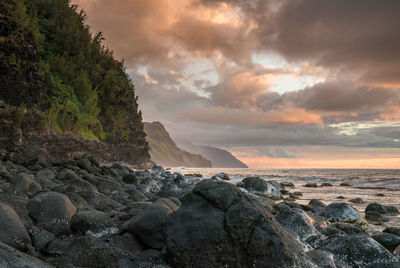 Rocks in sea against sky during sunset