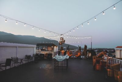 Chairs and tables in restaurant by sea against sky at dusk