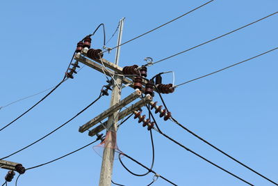 Low angle view of electricity pylon against clear sky