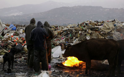 Rear view of people wearing raincoats while standing by garbage dump