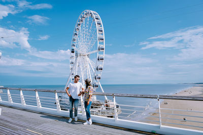 Ferris wheel by sea against sky