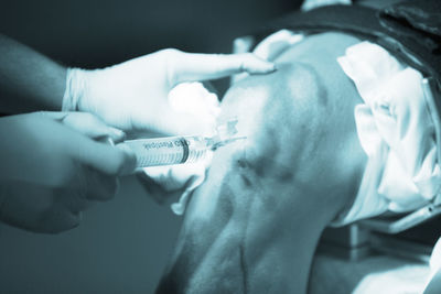 Cropped hands of doctor injecting patient at hospital