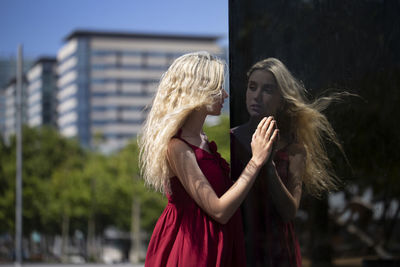Side view of young woman with blond hair reflecting on glass