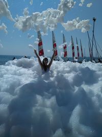 Woman standing amidst soap sud against sea at beach