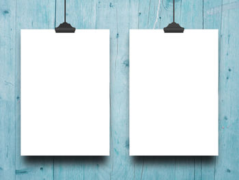 Close-up of blank papers hanging by wooden wall