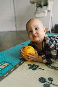 Cute baby girl playing with playing with an orange on a play mat.