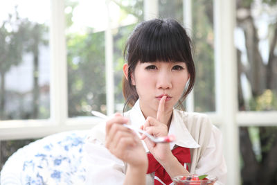 Portrait of woman with finger on lips eating food in cafe