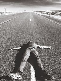 Full length of man lying on road during sunny day