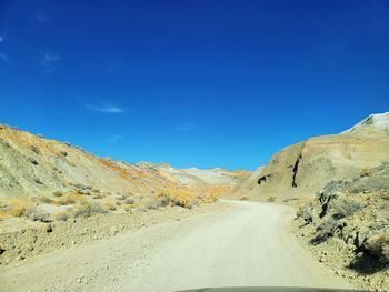 Road amidst mountains against blue sky