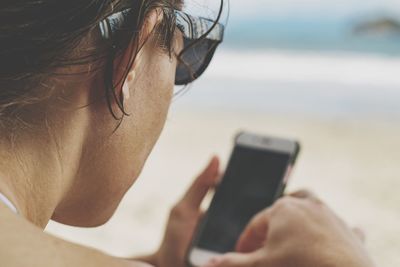 Close-up of woman using mobile phone at beach