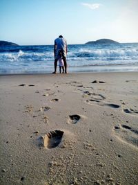 Rear view of man with child on beach