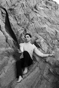 Young male with  androgynous look shot outdoor in black and white with rocks in background.