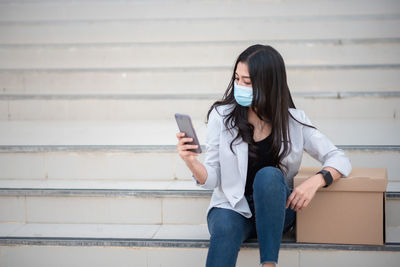 Young woman using mobile phone on staircase