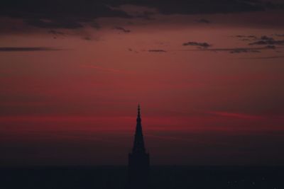 Silhouette of building against cloudy sky at sunset