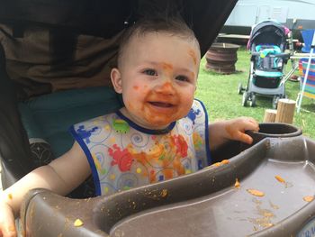 Close-up portrait of cute baby boy with messy face sitting on high chair