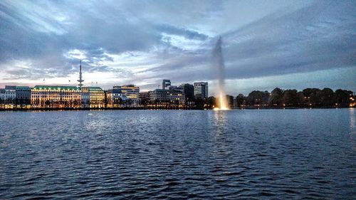 City at waterfront against cloudy sky