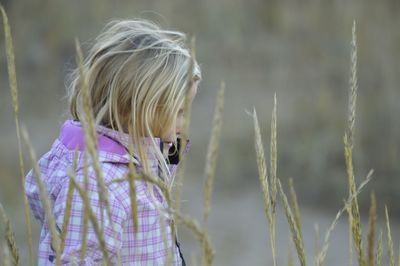 Side view of boy standing amidst plants on field