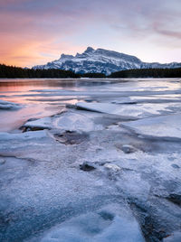 Colorful sunset on frozen lake with isolated mountain,two jack lake, banff np, alberta, canada