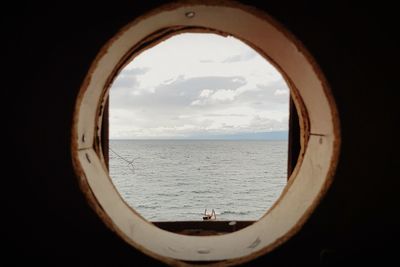 Close-up of sea against sky seen through arch