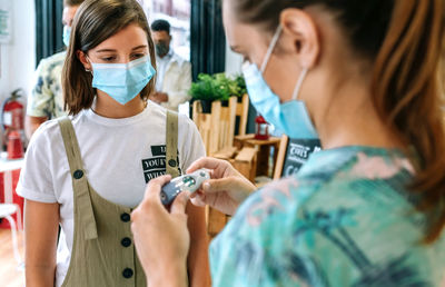 Woman checking temperature of woman in restaurant