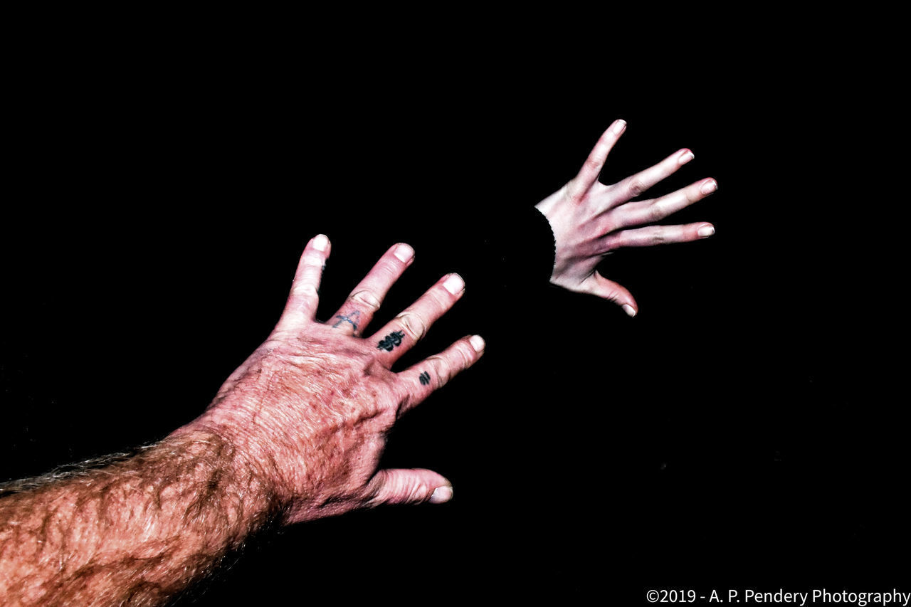 CLOSE-UP OF HANDS OVER BLACK BACKGROUND