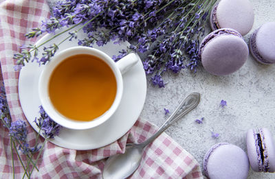 Cup of tea with lavender-flavored macaroon dessert and fresh lavender flowers