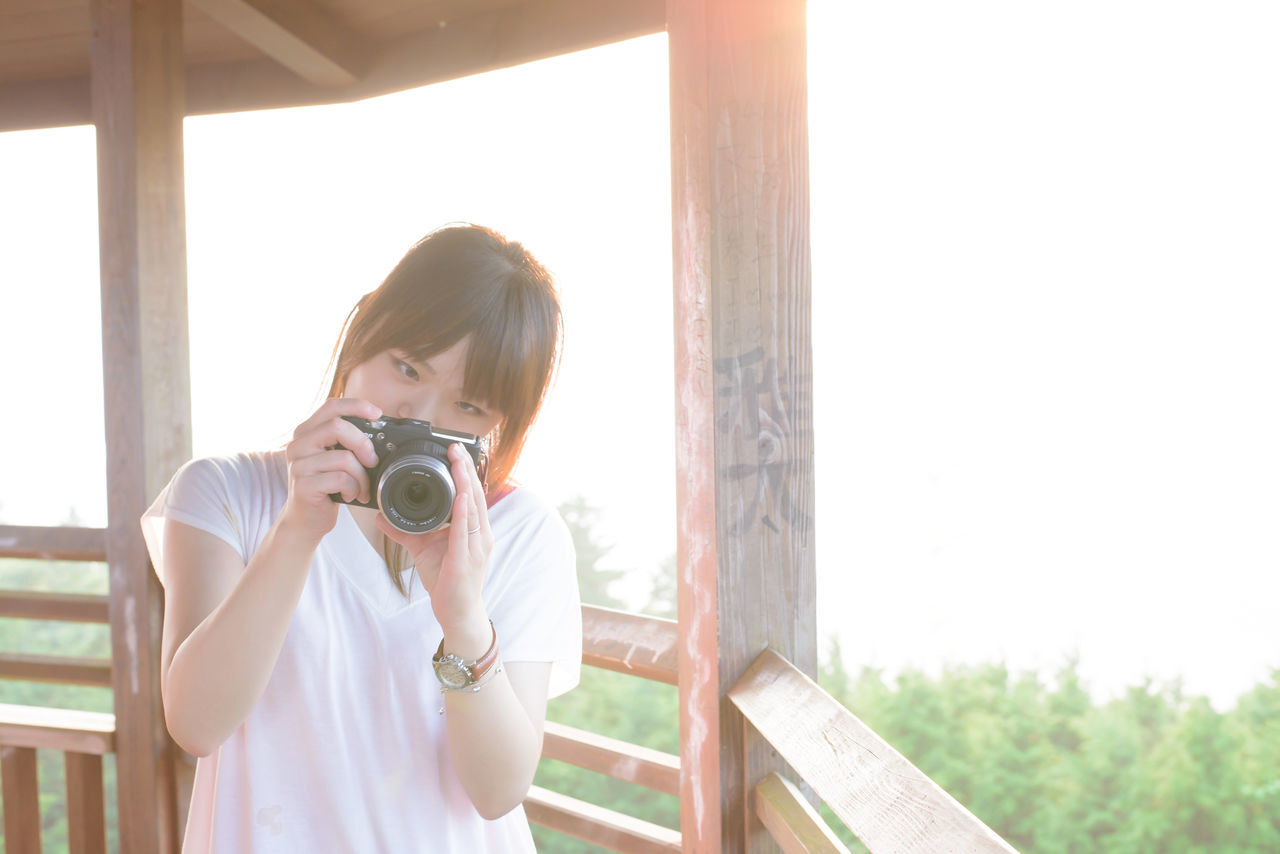 person, young adult, lifestyles, casual clothing, leisure activity, young women, railing, standing, smiling, three quarter length, built structure, indoors, window, portrait, looking at camera, wood - material, full length, sitting