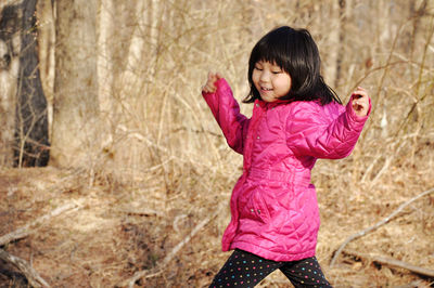 Full length of a cheerful girl in pink cloth against forest