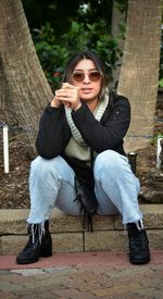 Portrait of young woman sitting on tree trunk