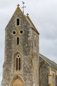 Low angle view of old a norman church against sky