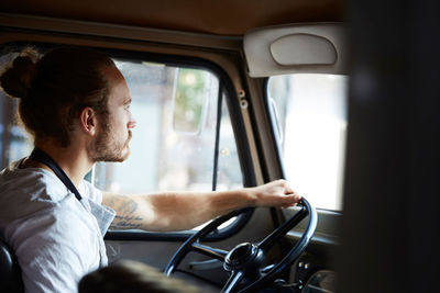 Side view of young man driving food truck in city